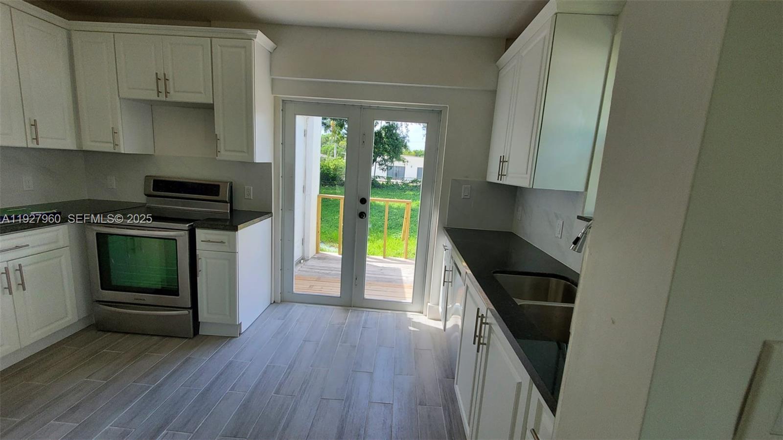 560 Northwest 53rd Street Miami, FL 33127 - Photo 8 of 12 a kitchen with granite countertop a stove a sink and a refrigerator