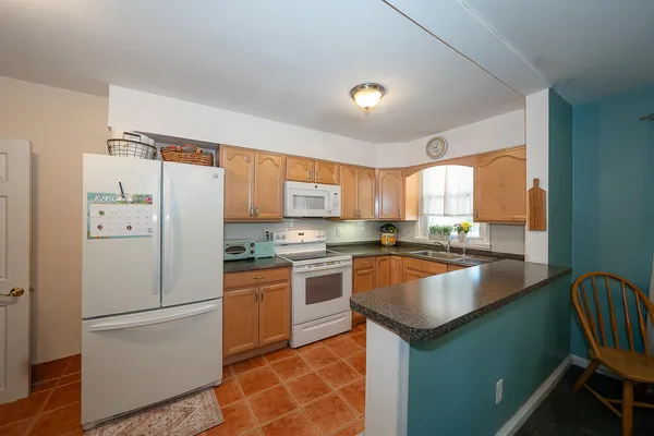 a kitchen with stainless steel appliances granite countertop a refrigerator a sink dishwasher a stove and white countertops with wooden floor