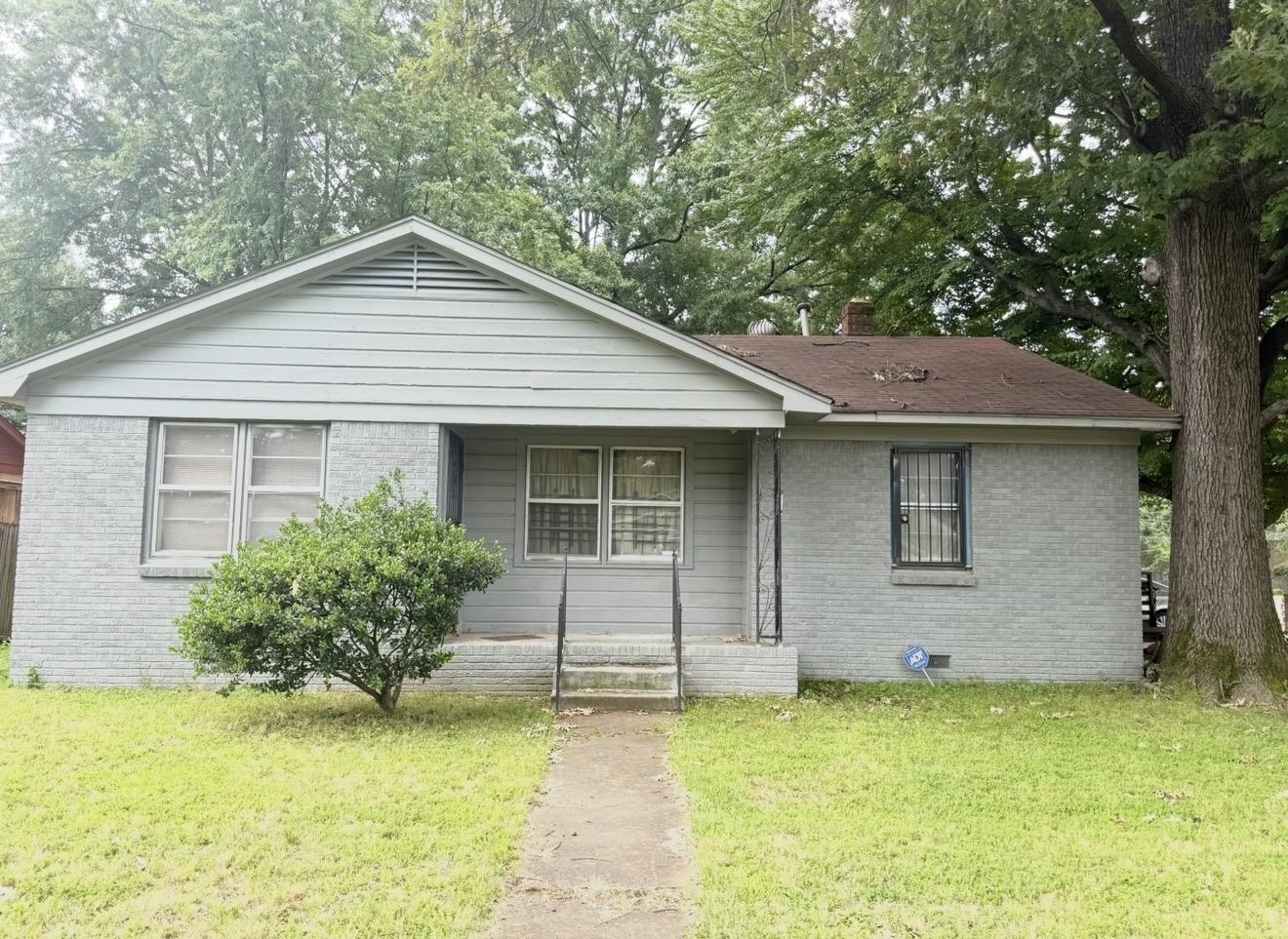2930 Getwell Road Memphis, TN 38118 - Photo 1 of 25 Single-story residence featuring a brick and siding exterior, a front entry with a small porch, and mature trees providing natural canopy