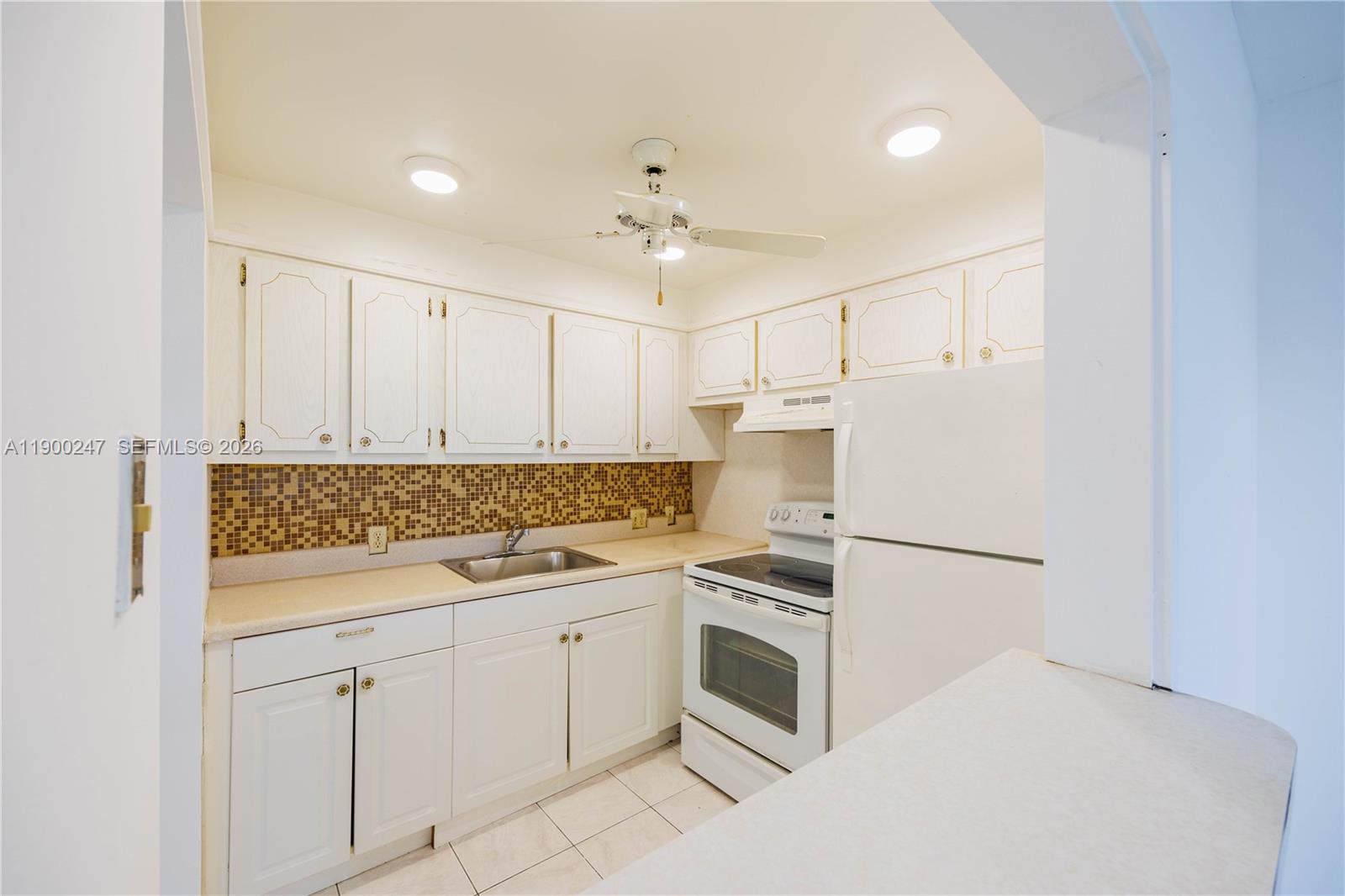 303 Preston H, Unit 303 Boca Raton, FL 33434 - Photo 11 of 50 a kitchen with white cabinets and white appliances