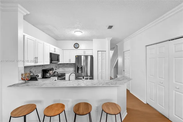 a kitchen with stainless steel appliances granite countertop a table chairs sink and cabinets