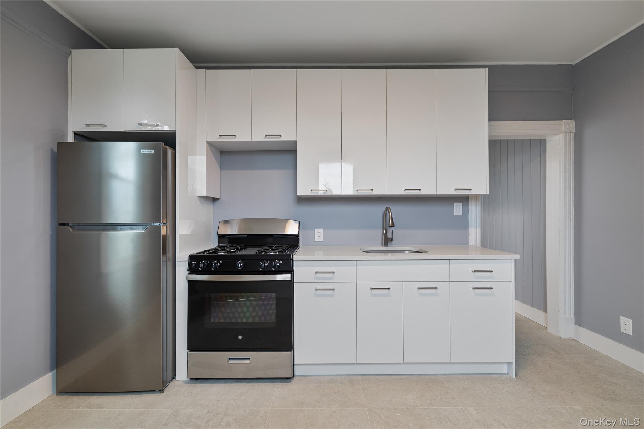 1 Elizabeth Place, Unit 1F Nyack, NY 10960 - Photo 3 of 23 Kitchen with range with gas stovetop, light countertops, freestanding refrigerator, white cabinets, and a sink
