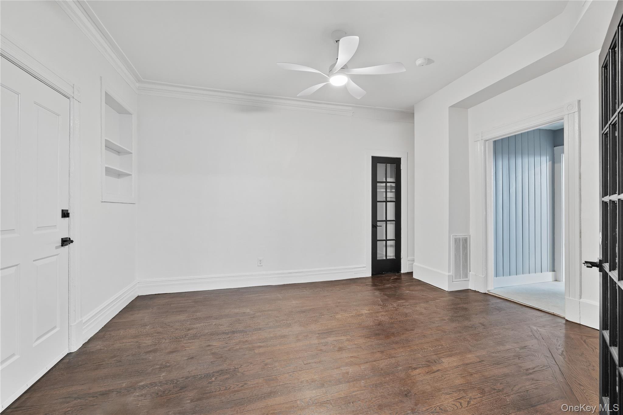 1 Elizabeth Place, Unit 1F Nyack, NY 10960 - Photo 9 of 23 Unfurnished room with dark wood-style flooring, ornamental molding, a ceiling fan, visible vents, and built in shelves
