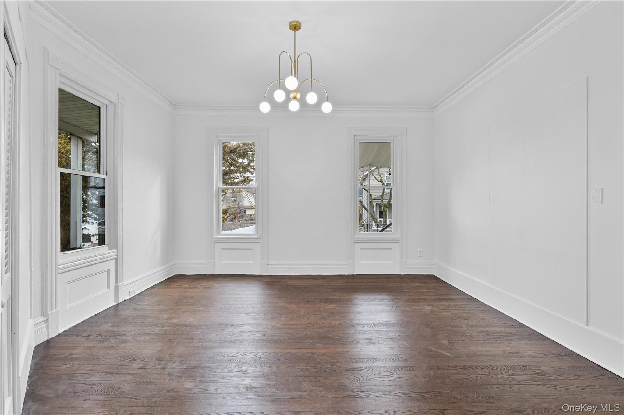 1 Elizabeth Place, Unit 1F Nyack, NY 10960 - Photo 10 of 23 Unfurnished dining area featuring crown molding, a decorative wall, a notable chandelier, and dark wood finished floors