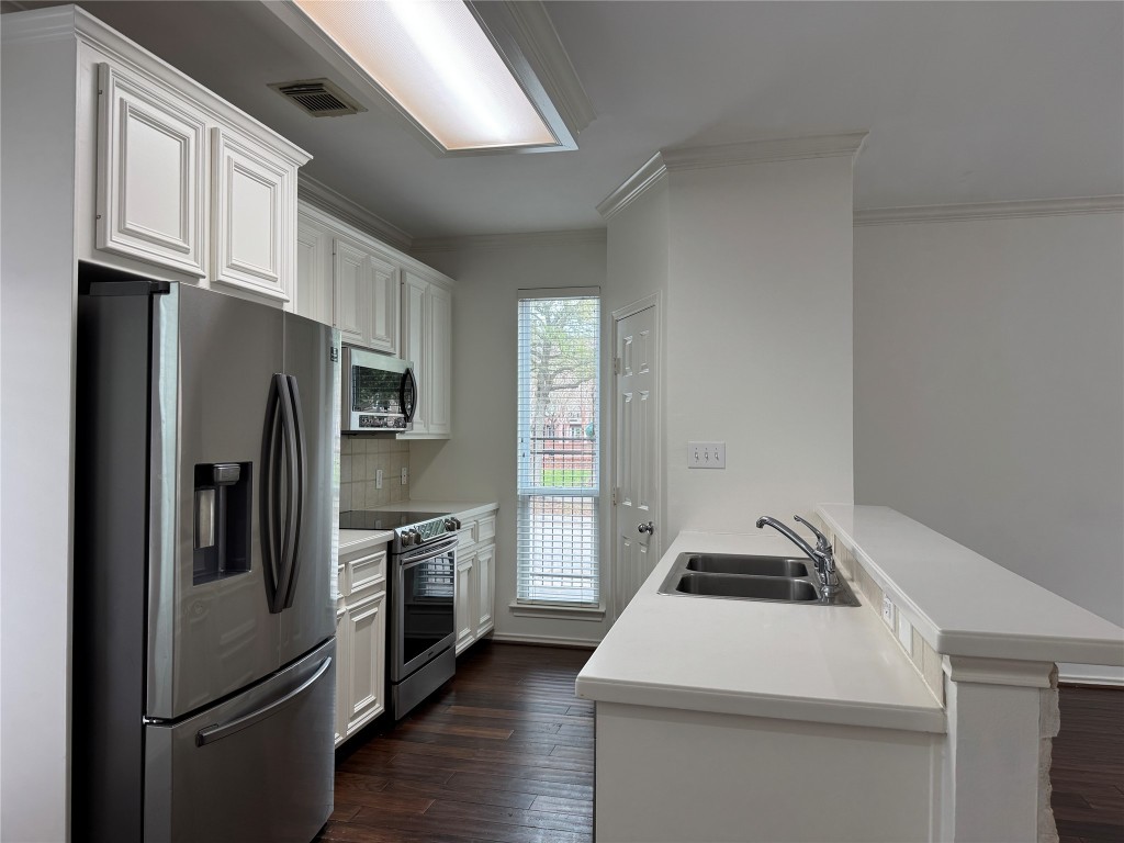 1908 Bailey Street Houston, TX 77006 - Photo 2 of 40 Your kitchen features stainless appliances, white cabinetry, a tile backsplash and Corian counters. You get a full-sized pantry and a view of the park across the street.