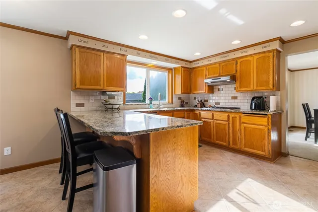 a kitchen with stainless steel appliances granite countertop table chairs sink and cabinets