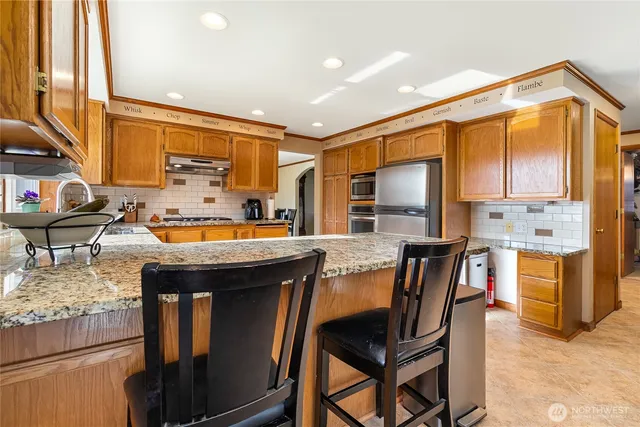 a kitchen with stainless steel appliances granite countertop a stove a sink and a refrigerator