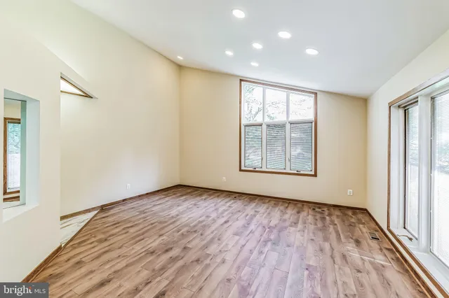 a view of empty room with wooden floor and fan