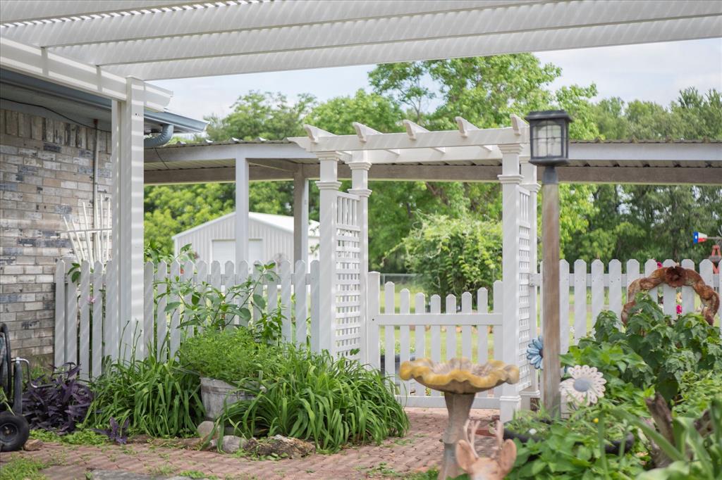 107 Fort Graham Circle Waco, TX 76705 - Photo 6 of 39 Outdoor living area featuring a louvered pergola covering, a white picket fence, and a garden archway