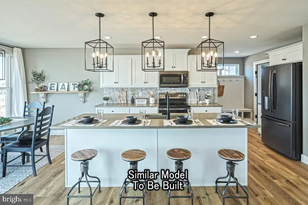 a kitchen with stainless steel appliances a dining table chairs and white cabinets