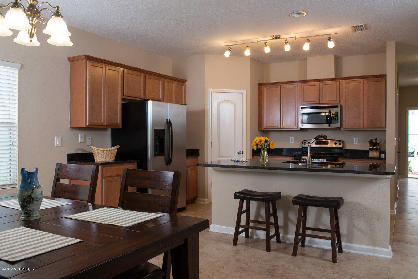 16365 Tisons Bluff Road Jacksonville, FL 32218 - Photo 5 of 25 a kitchen with stainless steel appliances granite countertop a refrigerator a stove a sink a dining table and chairs