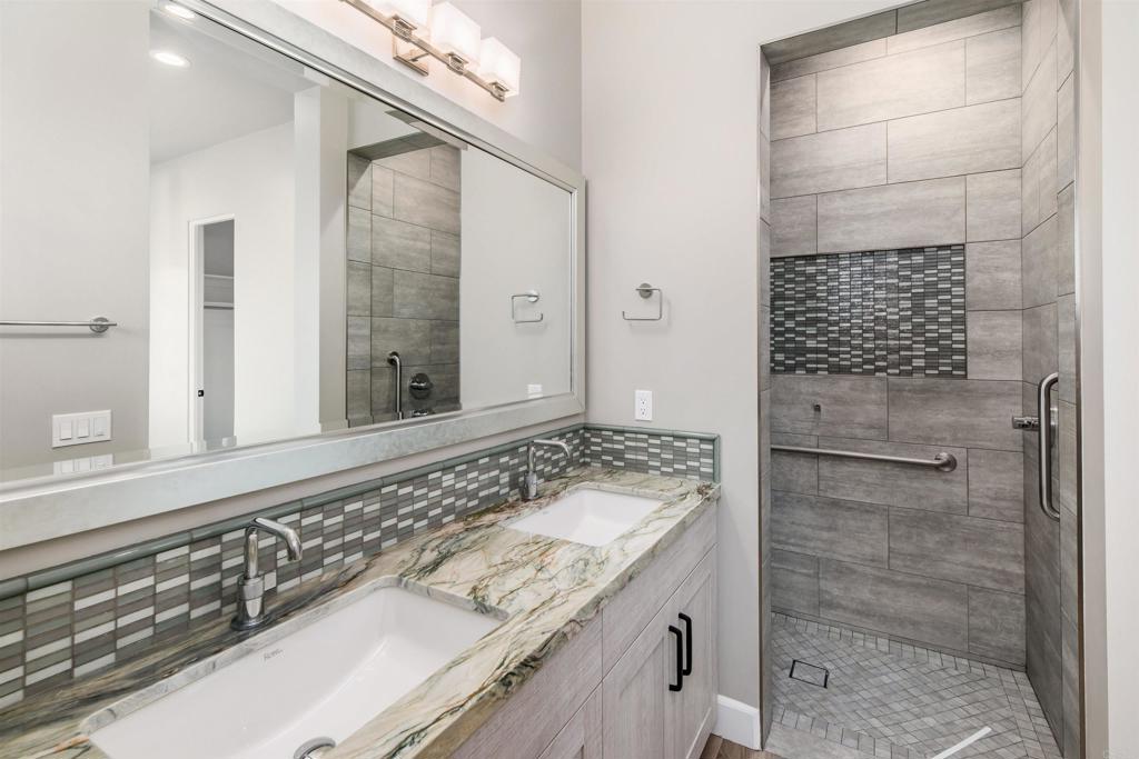 6768 Strawberry Place Carlsbad, CA 92011 - Photo 21 of 53 a bathroom with a granite countertop sink a mirror and shower