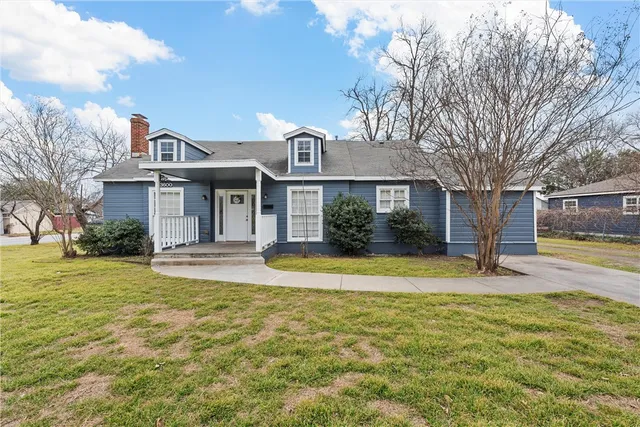 a view of a house with a small yard plants and large tree