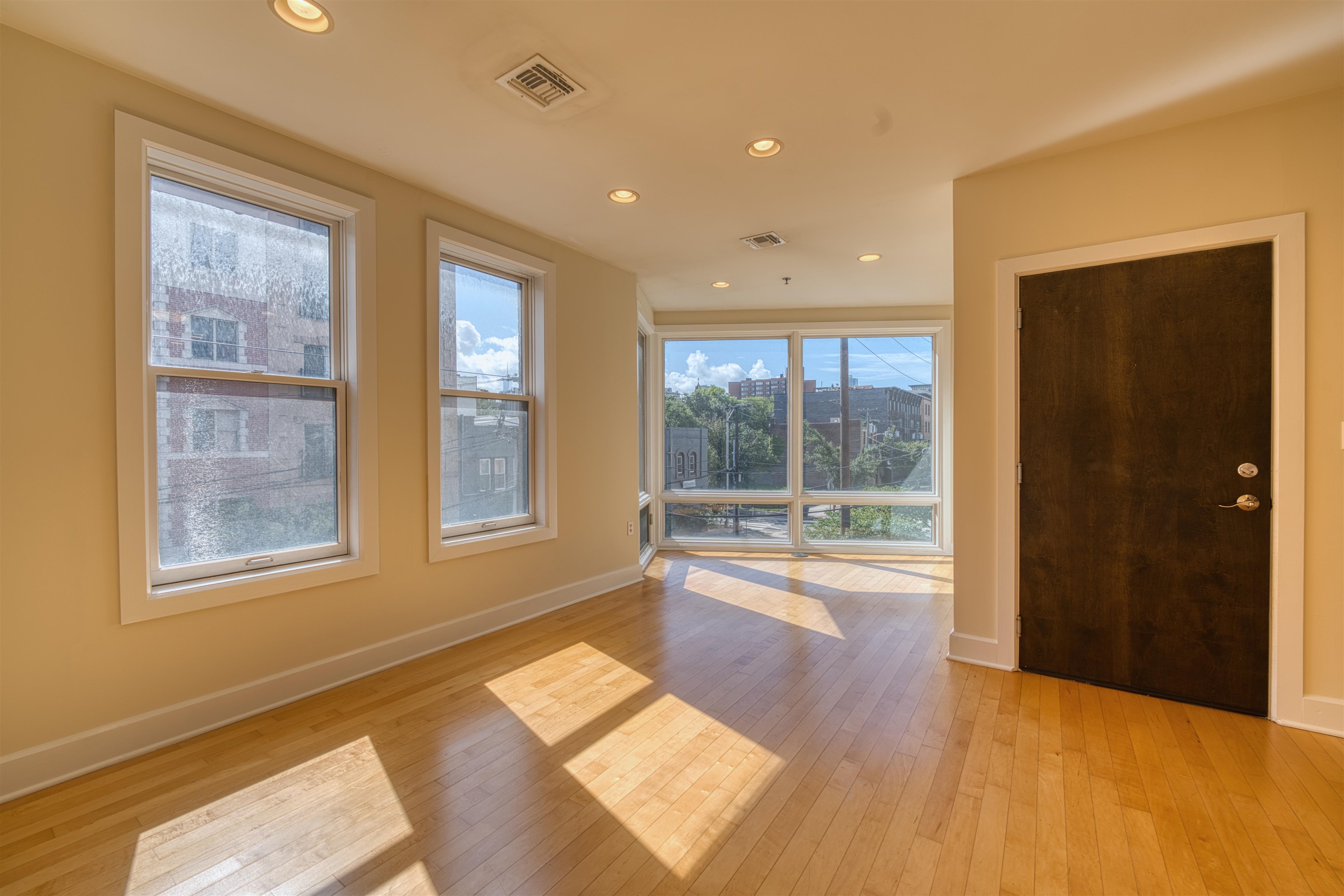 a view of an empty room with a window and wooden floor