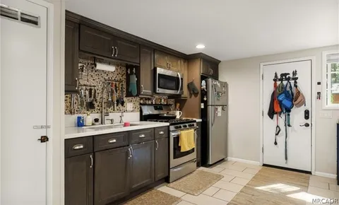 a view of kitchen with stainless steel appliances granite countertop a refrigerator and a sink