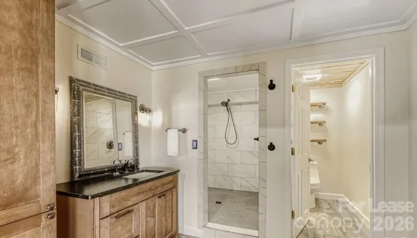 a bathroom with a granite countertop sink a mirror a glass door a shower and vanity
