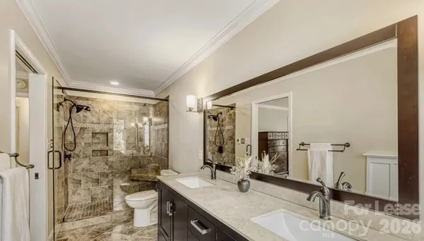 a bathroom with a double vanity sink toilet mirror and shower