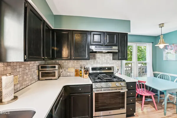 a kitchen with stainless steel appliances a stove a sink cabinets and a wooden floor
