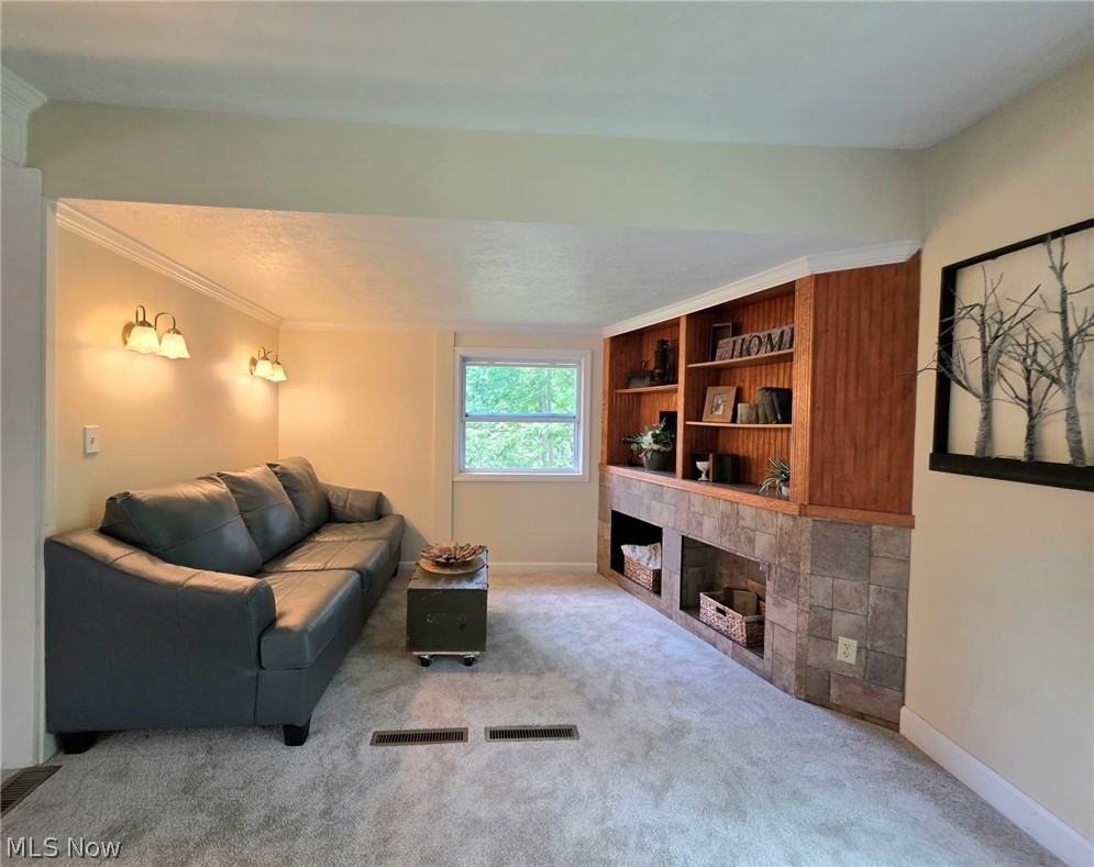 398 North Chillicothe Road Aurora, OH 44202 - Photo 9 of 39 Recessed living area featuring built-in wood shelving with stone-look base, wall sconces, a window providing natural light, and plush carpeting