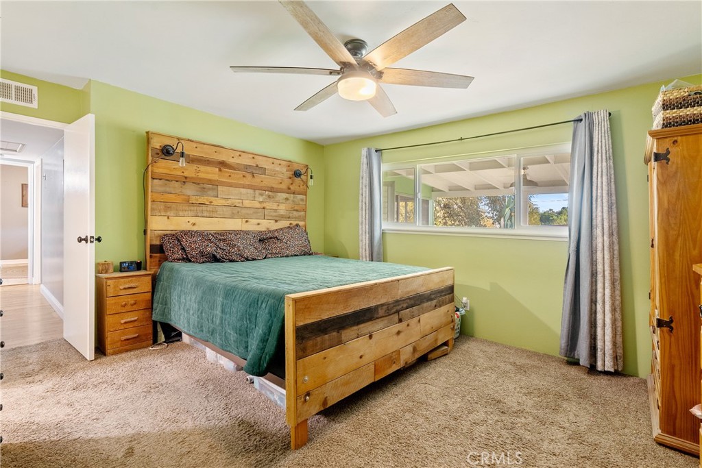 8892 Palomar Avenue Atascadero, CA 93422 - Photo 20 of 49 Primary bedroom with plush carpeting, a large window, and a ceiling fan create a bright and comfortable space.