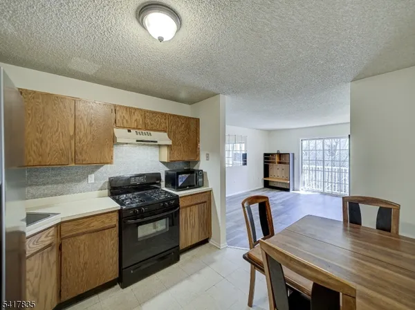 a kitchen with granite countertop a stove a sink dishwasher a dining table and chairs with wooden floor