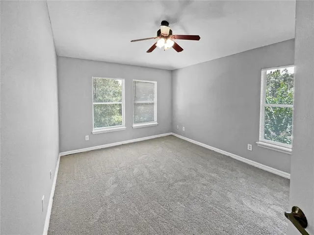 an empty room with windows and ceiling fan