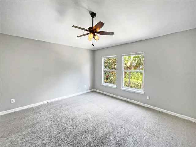 an empty room with windows and fan