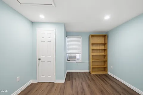 an empty room with wooden floor closet and windows