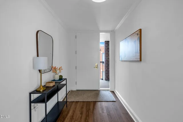 a view of a hallway with wooden floor and a bathroom