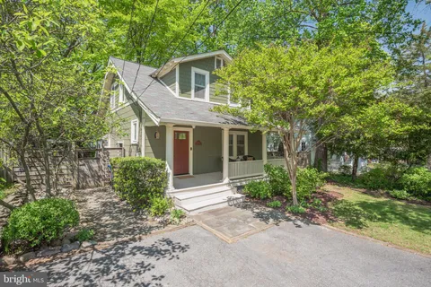 a front view of a house with garden and trees