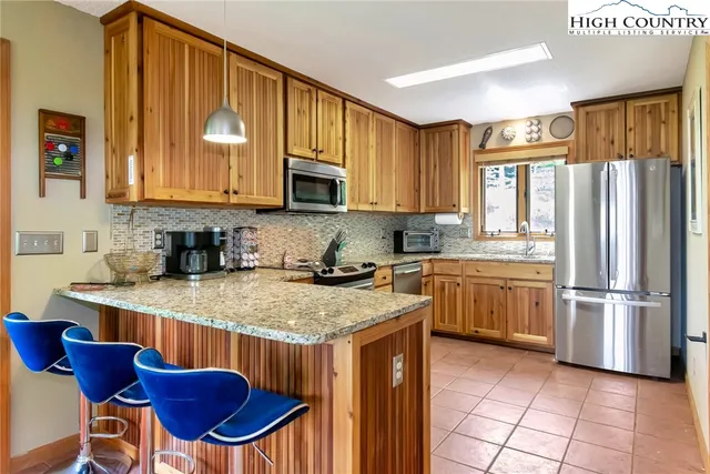 a kitchen with granite countertop a stove top oven microwave and refrigerator