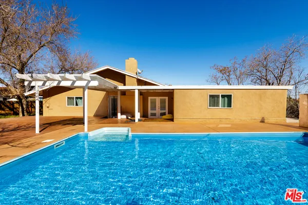 a view of a house with pool and a yard