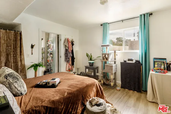 a bedroom with a bed a table and a large mirror with wooden floor