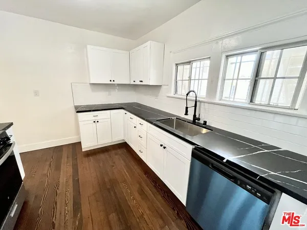 a kitchen with a sink wooden floor and cabinets