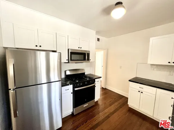 a kitchen with a refrigerator a white cabinets and wooden floor