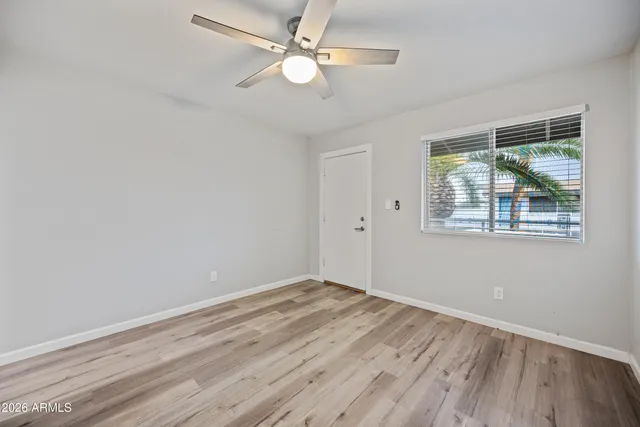 an empty room with wooden floor ceiling fan and windows