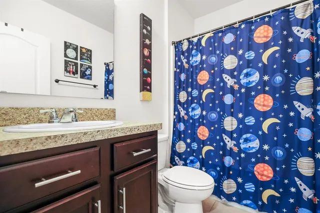 a bathroom with a granite countertop sink and a toilet
