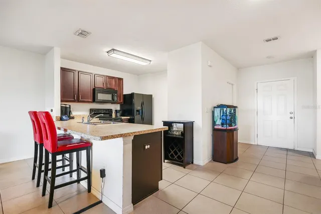 a kitchen with stainless steel appliances a refrigerator a stove a sink a dining table and chairs