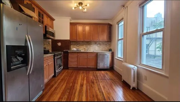 a kitchen with stainless steel appliances a refrigerator sink and wooden floor