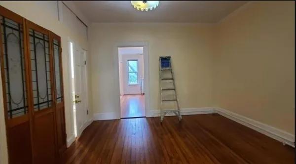 a view of empty room with wooden floor and fan