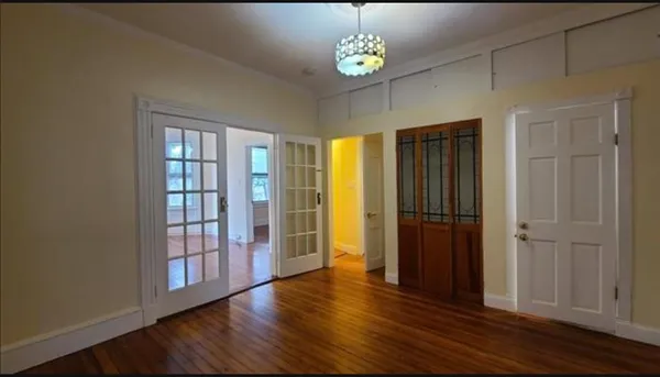 an empty room with wooden floor cabinet and windows