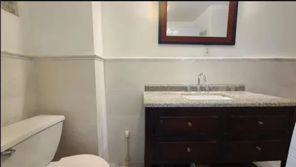 a bathroom with a granite countertop sink and a toilet