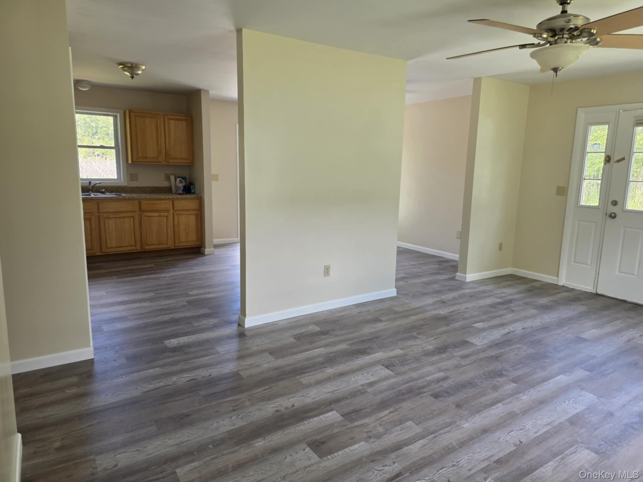 105-107 East Cold Spring Road Monticello, NY 12701 - Photo 15 of 22 Unfurnished living room with healthy amount of natural light, dark wood finished floors, and a ceiling fan