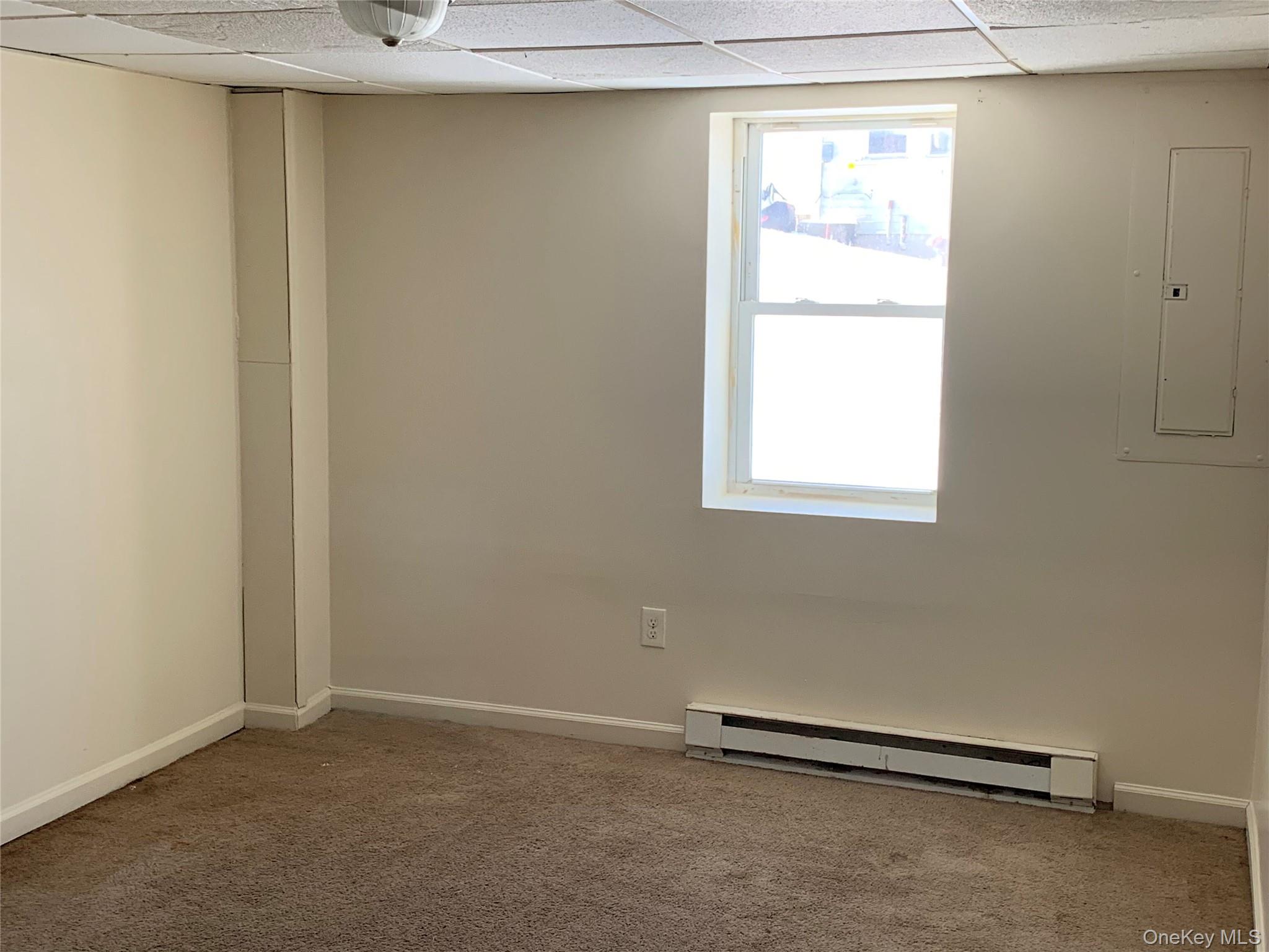 105-107 East Cold Spring Road Monticello, NY 12701 - Photo 3 of 22 Carpeted spare room featuring a drop ceiling, a baseboard heating unit, and electric panel