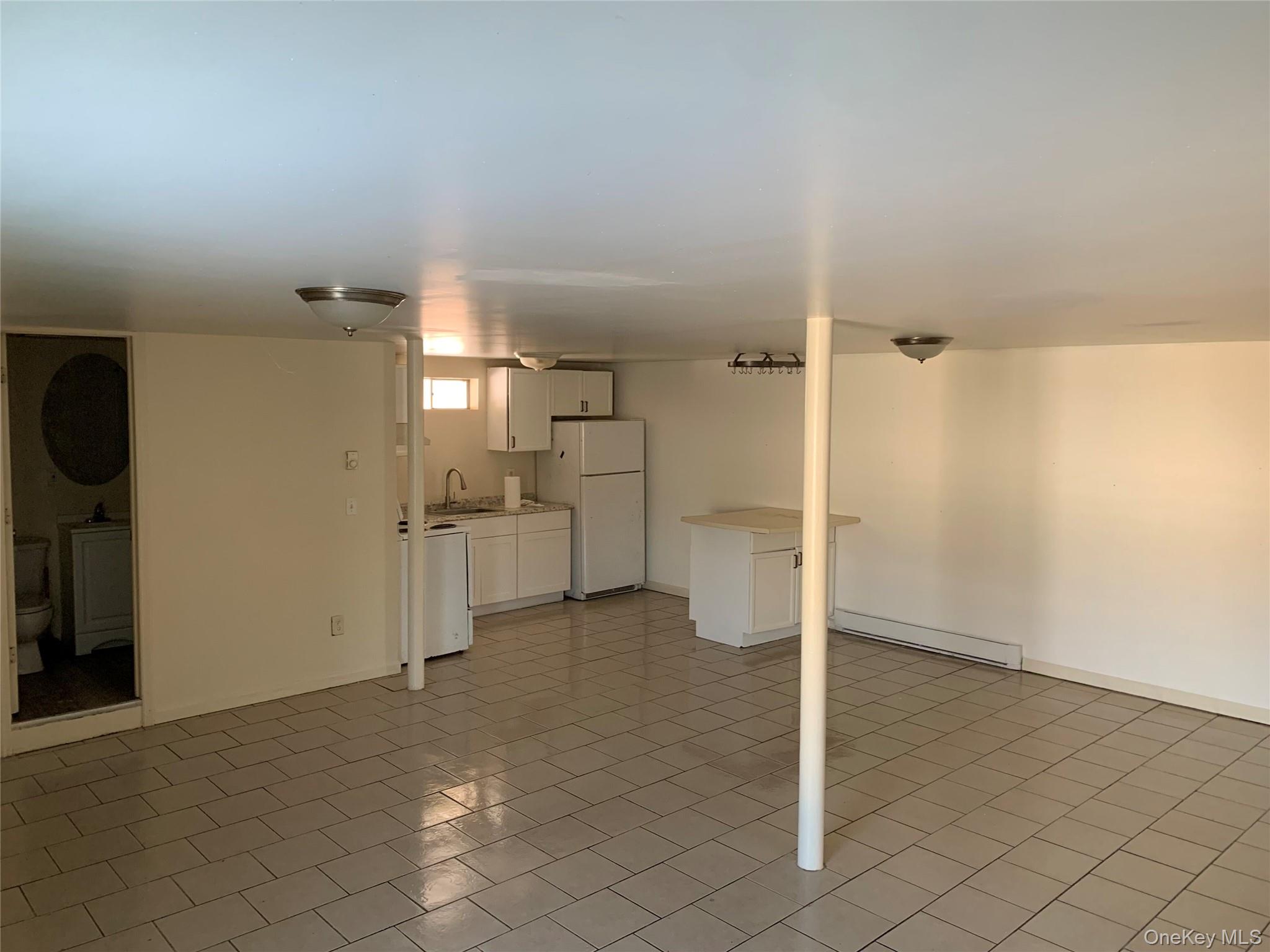 105-107 East Cold Spring Road Monticello, NY 12701 - Photo 6 of 22 Basement featuring a baseboard radiator and freestanding refrigerator