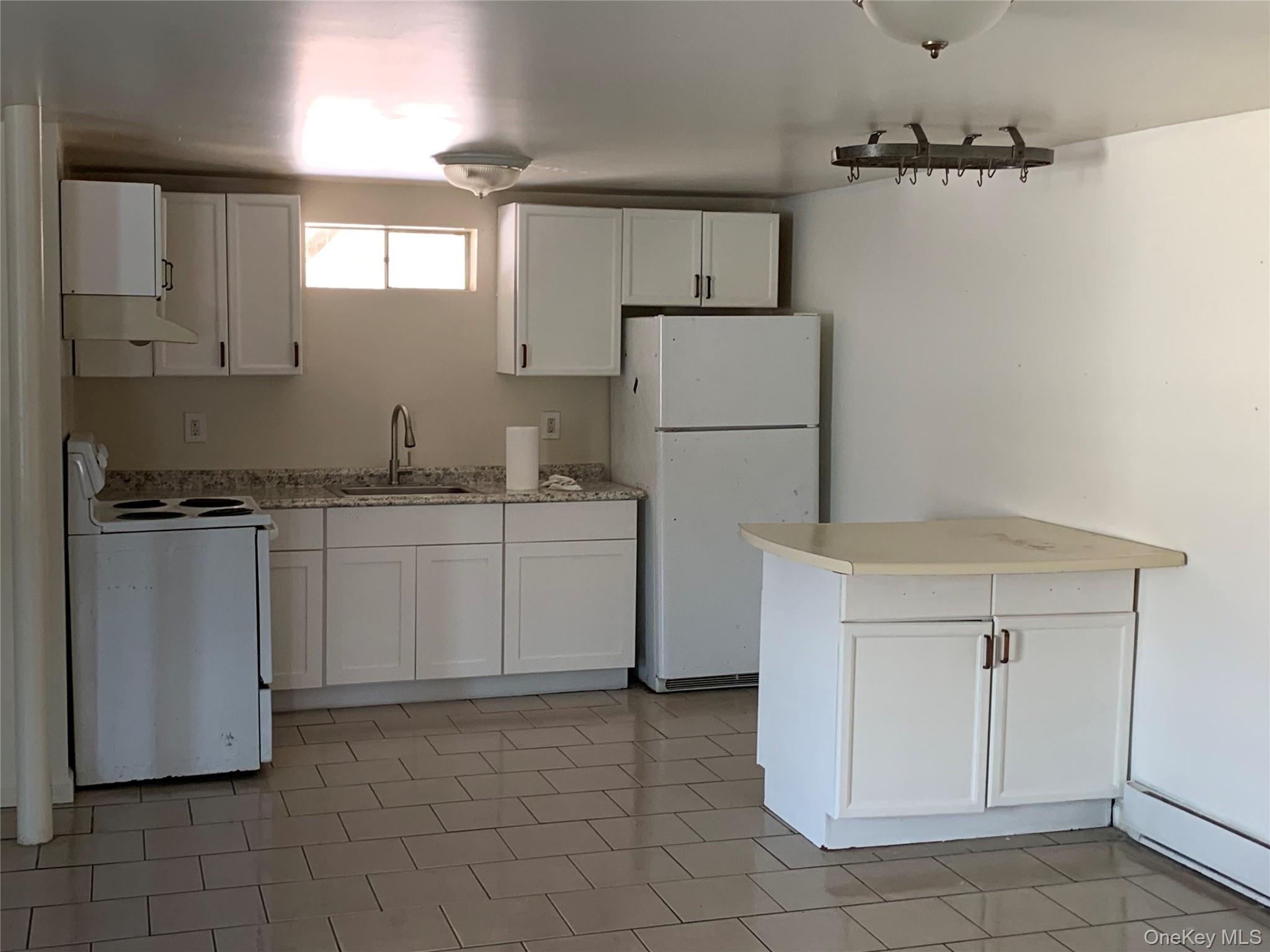 105-107 East Cold Spring Road Monticello, NY 12701 - Photo 7 of 22 Kitchen featuring white appliances, white cabinets, under cabinet range hood, and a peninsula