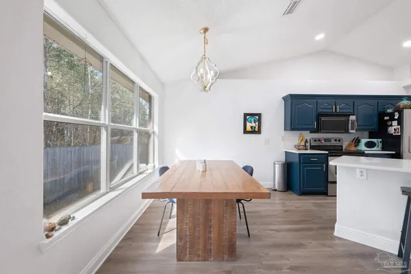 a living room with stainless steel appliances furniture a chandelier a rug and a window