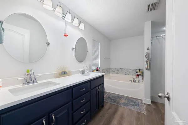 a spacious bathroom with a double vanity sink a mirror and a bathtub