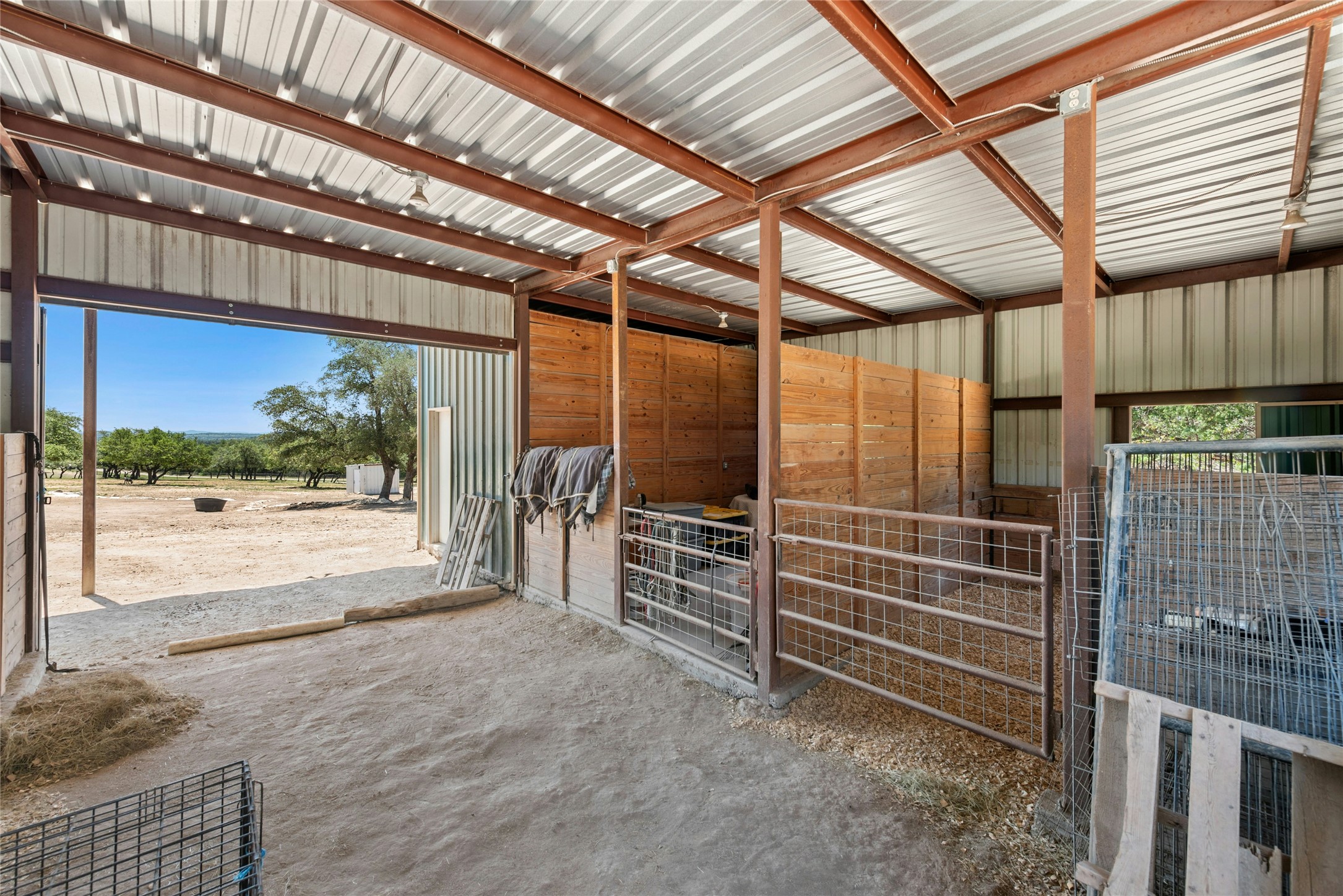 496 Middleton Road Spicewood, TX 78669 - Photo 29 of 40 Metal-sided barn structure featuring an open entrance, interior stalls with wood paneling, and a corrugated metal roof
