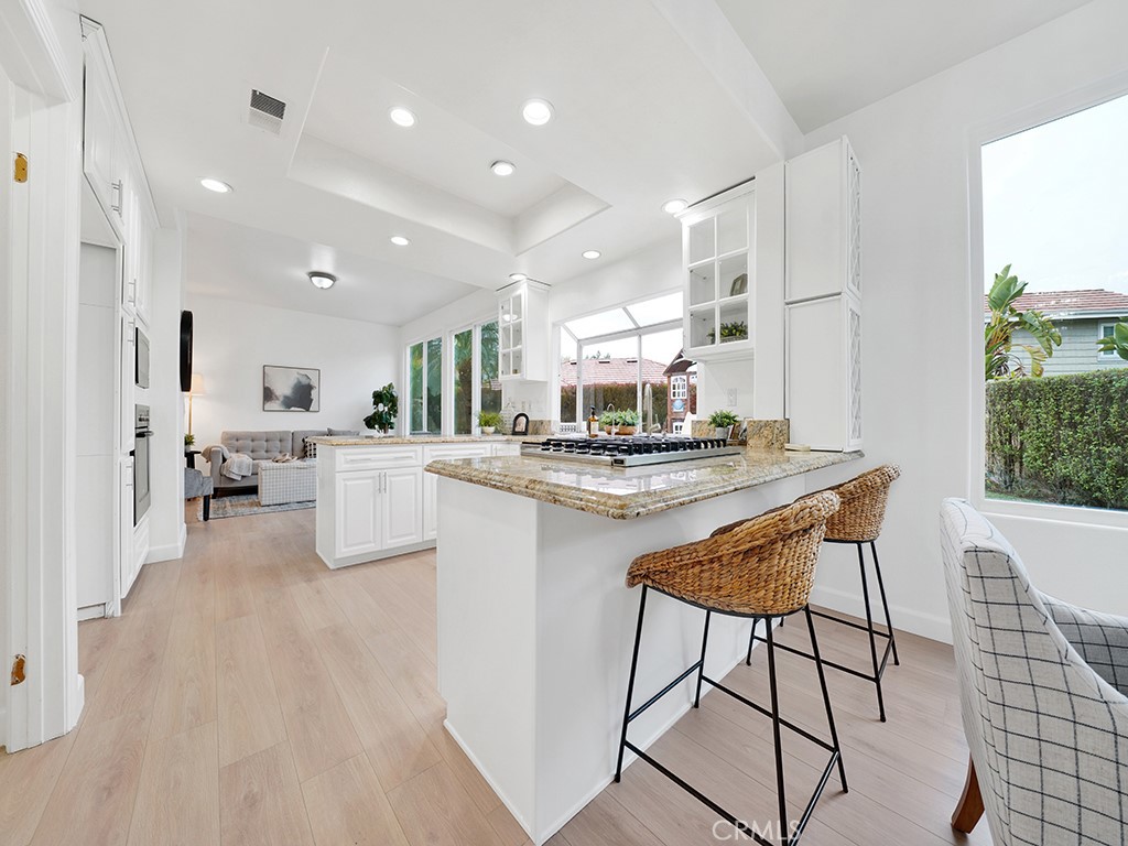 13814 Apache Tustin, CA 92782 - Photo 9 of 45 a kitchen with stainless steel appliances kitchen island granite countertop a stove a sink a refrigerator and white cabinets with wooden floor